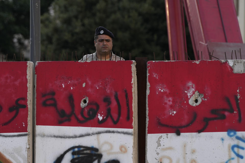 An army soldier watches policemen remove barbed wire barriers blocking streets that lead to the Parliament and other government buildings in Beirut, Lebanon, Thursday, May 26, 2022. Parliament Speaker Nabih Berri called for the new Parliament to hold its first session to elect a speaker and deputy parliament speaker next Tuesday. (AP Photo/Hassan Ammar)