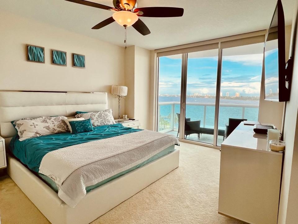 The primary suite offers an oversized garden tub with jets, a glass-enclosed tiled shower with a sit-down bench and sliders offering waterfront views and access to the patio area.