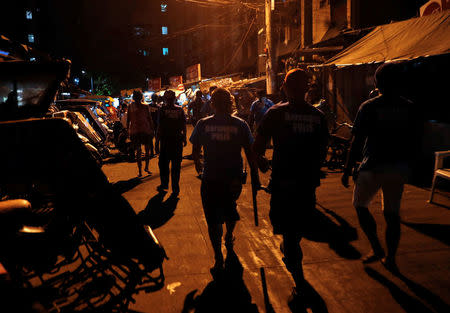 Policemen and Barangay watchmen patrol as they look for teenagers lingering in the streets in Tondo, Manila, Philippines July 2, 2018. REUTERS/Erik De Castro/Files