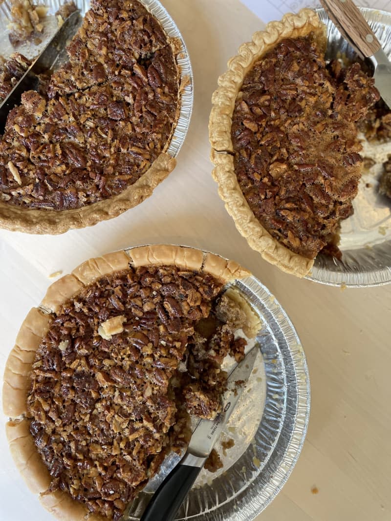 3 pecan pies in silver pie tins with pieces taken out