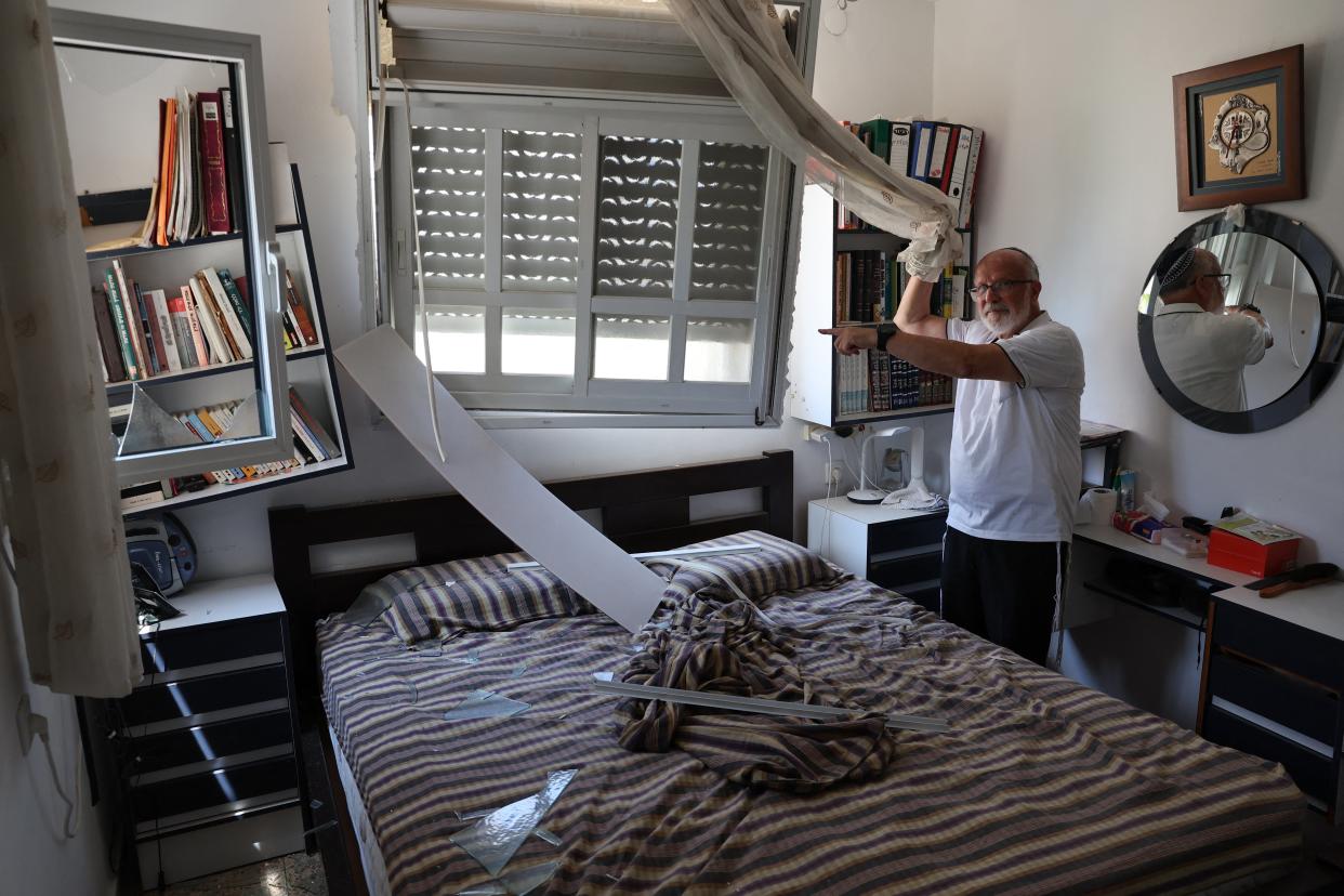 A resident points at the damage inside a house caused by a rocket fired from Lebanon in the Israeli coastal town of Acre (AFP via Getty Images)