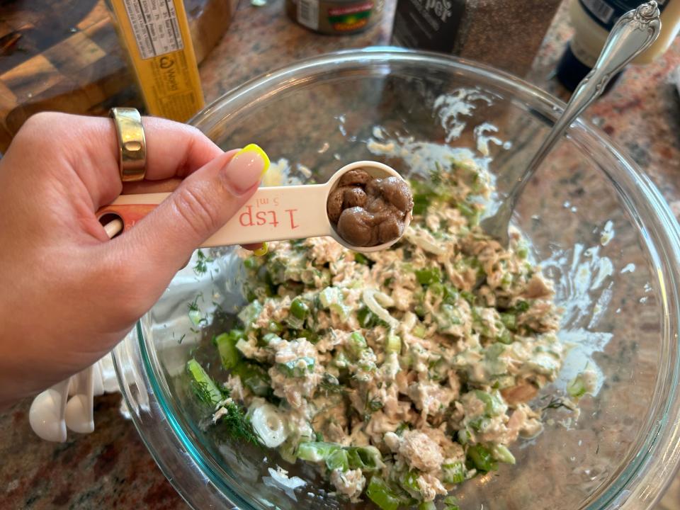 A tuna mixture with mayonnaise and a teaspoon of anchovy paste being added in.