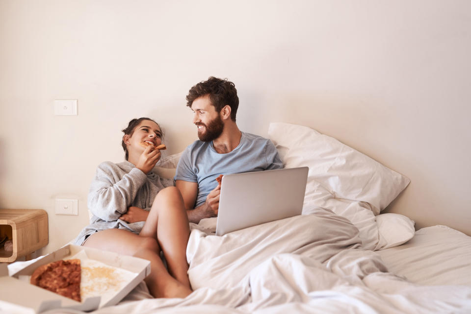 Eating pizza in bed couple. (Getty Images)