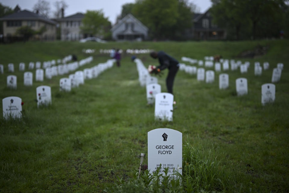 Community members lay flowers down near gravestone markers at the 'Say Their Names' cemetery Wednesday, May 25, 2022, in Minneapolis. The intersection where George Floyd died at the hands of Minneapolis police officers was renamed in his honor Wednesday, among a series of events to remember a man whose killing forced America to confront racial injustice. (Aaron Lavinsky/Star Tribune via AP)