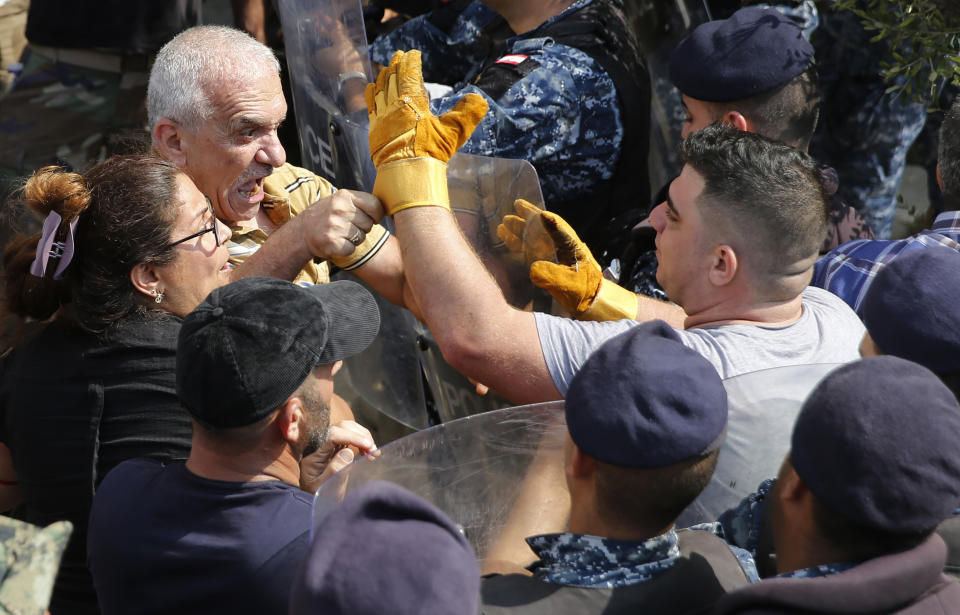 Lebanese retired soldiers, left, clash with riot police, as they try to enter the parliament building where lawmakers and ministers are discussing the draft 2019 state budget, in Beirut, Lebanon, Friday, July 19, 2019. The budget is aimed at averting a financial crisis in heavily indebted Lebanon. But it was met with criticism for failing to address structural problems. Instead, the budget mostly cuts public spending and raises taxes. (AP Photo/Hussein Malla)