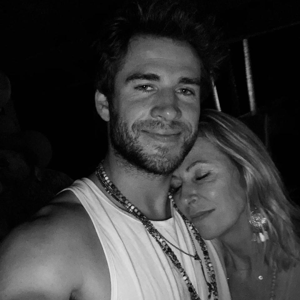 Liam Hemsworth smiling at the camera with his mum resting on his shoulder