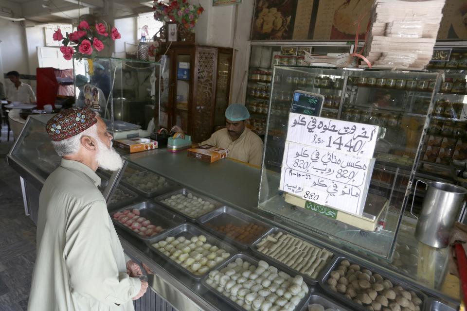 A man buys sweet at a famous 67-year-old sweet shop run by a Hindu businessman, in Shikarpur, Pakistan, Wednesday, Oct. 26, 2022. The landscape of Pakistan, and Sindh in particular, retains their imprint. It has temples, although their numbers have plummeted, businesses, education and healthcare institutions, many established before the country was created in 1947. These places are part of Pakistan's heritage, even as Hindus are forced into the shadows. (AP Photo/Fareed Khan)