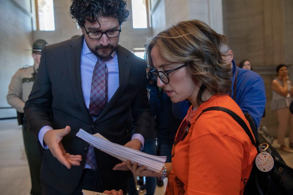 Sarah Shoop Neumann, a parent of a Covenant School student, hands a letter with more than 5,000 signatures opposing a bill that would allow teachers to carry guns to an aide at the Tennessee Capitol in Nashville, Tenn., Monday, April 22, 2024.