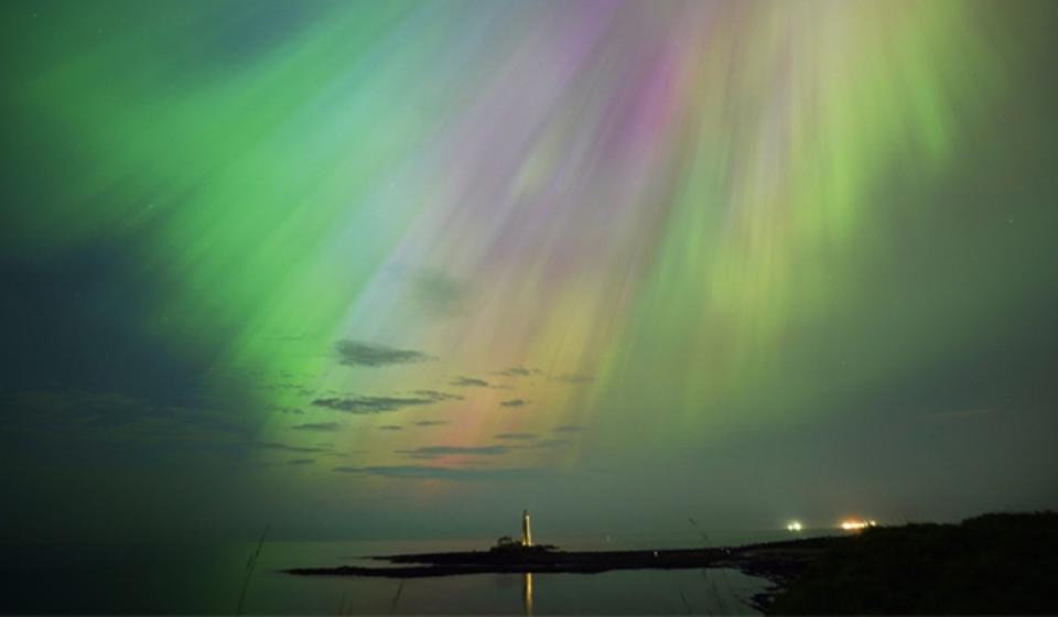The aurora borealis, also known as the northern lights, glow in the sky over St Mary’s Lighthouse in Whitley Bay on the North East coast on 10 May, 2024 (PA)