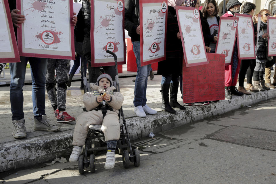 FILE - In this Jan. 13, 2018 file photo, family members of Tunisians who died in the revolution seven years ago, stage a protest in Tunis, while a child in a baby-stroller rests in front of them. Since winning a parliamentary seat in 2019, Tunisian lawmaker Abir Moussi has become one of the country’s most popular, and most controversial, politicians, riding a wave of nostalgia for a more stable and prosperous time, just as Tunisia marks 10 years since protesters overthrew autocratic former President Zine El Abidine Ben Ali. Since 2011, Tunisia has been plagued by sinking wages, growing joblessness and worsening public services. Unemployment has risen amid the coronavirus pandemic from 15% to 18%. Attempts to migrate to Europe by sea have soared. (AP Photo/Hassene Dridi, File)