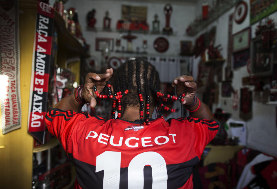 In this April 28, 2014 photo, Maria Boreth de Souza, alias Zica, shows her braids decorated with beads in the colors of her favorite team, Flamengo, at her home in the Olaria neighborhood of Rio de Janeiro, Brazil. Zica is a well-known sight in her neighborhood or in the football stadium. (AP Photo/Leo Correa)