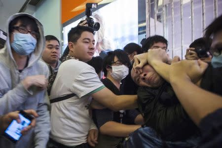 Protesters restrain a man (R) who allegedly beat other protesters during a demonstration inside a shopping mall in Hong Kong in this February 15, 2015 file photo. REUTERS/Tyrone Siu/Files