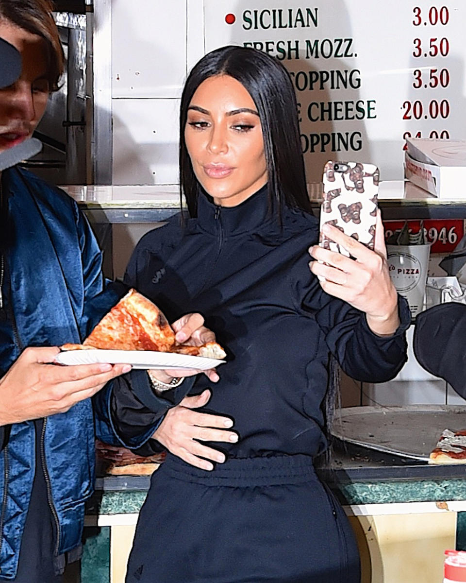 <p>What will Mama Kardashian say to young North and Saint when they won’t look up from their phones at the dinner table? The reality star can’t put hers down long enough to enjoy a slice of New York pizza! (Photo: Robert Kamau/GC Images) </p>