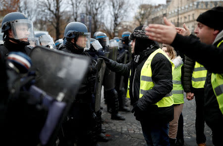 A protester wearing yellow vest, a symbol of a French drivers' protest against higher fuel prices, talks to the police officer in Paris, France, November 24, 2018. REUTERS/Benoit Tessier