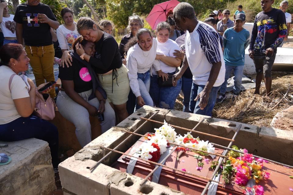 Relatives of miner Santiago Mora cry during his buried at the cemetery in La Paragua, Bolivar state, Venezuela, Thursday, Feb. 22, 2024. The collapse of an illegally operated open-pit gold mine in central Venezuela killed at least 14 people and injured several more, state authorities said Wednesday, as some other officials reported an undetermined number of people could be trapped. (AP Photo/Ariana Cubillos)