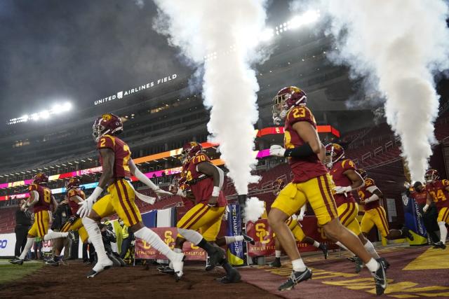 USC football players run on to the field before the 2020 Pac-12 title game against Oregon at the Coliseum.
