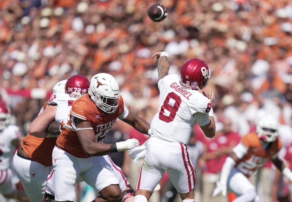 Oklahoma Sooners quarterback Dillon Gabriel (8) passes the ball as he advoids the sack from Texas Longhorns defensive lineman Vernon Broughton (45) in the third quarter during an NCAA college football game at the Cotton Bowl on Saturday, Oct. 7, 2023 in Dallas, Texas. This game makes up the119th rivalry match up.