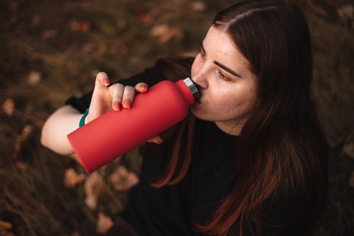 A woman is drinking out of a reusable water bottle.