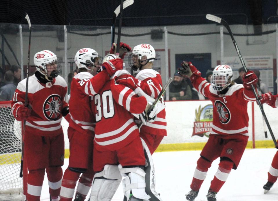 Teammates mob Spaulding High School goalie Collin McIntyre (30) following his 42-save effort in the Red Raiders' Division II semifinal win over Dover on Wednesday, March 6, 2024 at Everett Arena in Concord.