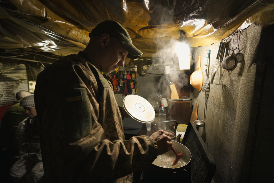 A Ukrainian serviceman cooks in a bunker on a frontline position outside Avdiivka, Donetsk region, eastern Ukraine, Friday, Feb. 4, 2022. Washington is raising the rhetoric about the buildup of Russian forces near Ukraine's border, but the Ukrainian president is projecting calm. (AP Photo/Vadim Ghirda)