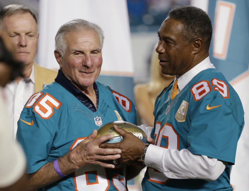 FILE - In this Dec. 14, 2015, file photo, former Miami Dolphins player Nick Buoniconti (85) is presented a football by former player and current Dolphins senior vice president of special projects and alumni relations, Nat Moore (89) during the Dolphins All-Time 50th Anniversary Team ceremony during half time at an NFL football game against the New York Giants, in Miami Gardens, Fla. Pro Football Hall of Fame middle linebacker Nick Buoniconti, an undersized overachiever who helped lead the Miami Dolphins to the NFL's only perfect season, has died at the age of 78. Bruce Bobbins, a spokesman for the Buoniconti family, said he died Tuesday, July 30, 2019, in Bridgehampton, N.Y. (AP Photo/Wilfredo Lee, File)