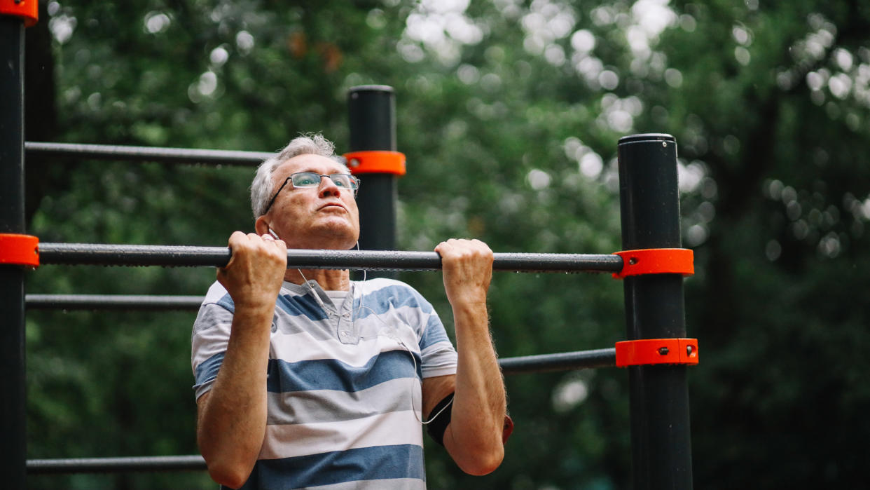 Mature man exercising in the public park, trying to stay fit and healthy at older age.