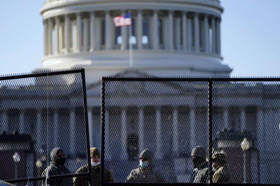 With the U.S. Capitol in the background, members of the National Guard stand behind newly placed fencing around the Capitol grounds the day after violent protesters loyal to President Donald Trump stormed the U.S. Congress in Washington, Thursday, Jan. 7, 2021. (AP Photo/Evan Vucci)