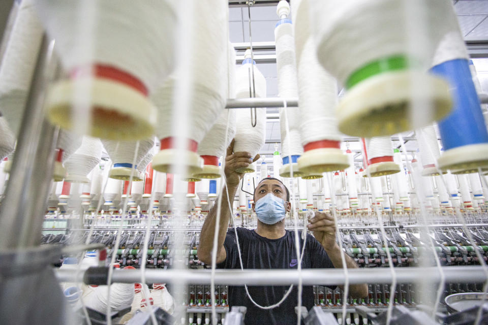 KUQA, CHINA - MARCH 25: A worker handles spools of yarn on a production line at a workshop of Xinjiang Xieyi Textile Technology Co., Ltd on March 25, 2021 in Kuqa, Xinjiang Uygur Autonomous Region of China. (Photo by Yuan Huanhuan/VCG via Getty Images)