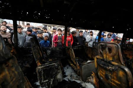 People look at a burned vehicle at the site of car bomb attack in a busy square at Baghdad's sprawling Sadr City district, in Iraq January 2, 2017. REUTERS/Ahmed Saad