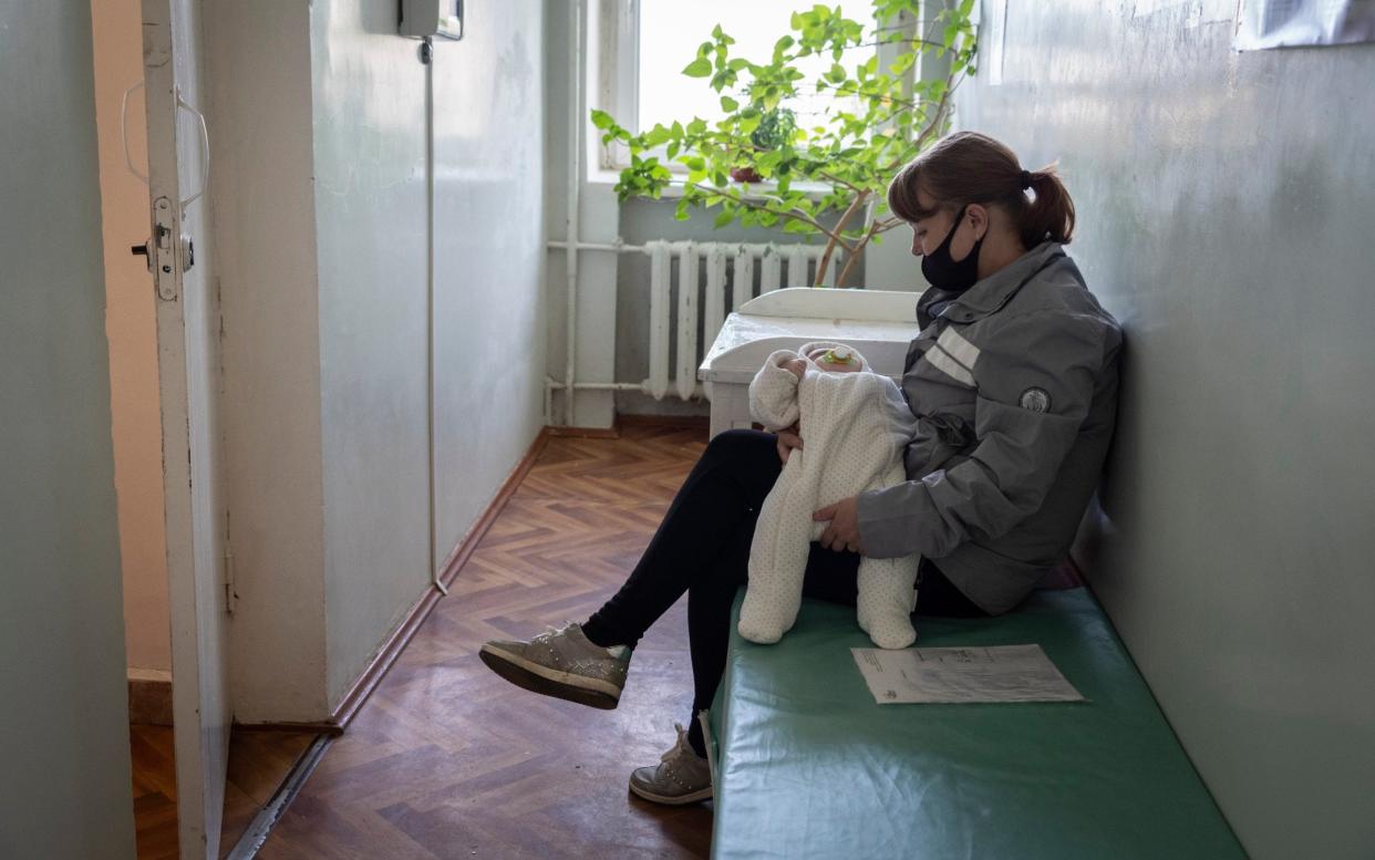 A woman waits with her baby in the waiting room of a doctor's surgery - Andrey Borodulin 