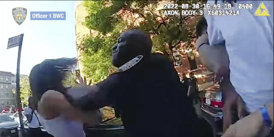 This still image from New York City Police Department body camera video, shows an incident Tuesday, Aug. 30. 2022, in which a detective shoved a woman to the ground after she struck him while he was helping officers arrest an attempted murder suspect in New York's Harlem neighborhood. The woman was one of three people involved in the incident who were arrested for interfering with police and charged with obstructing governmental administration, a misdemeanor. (New York City Police Department via AP)