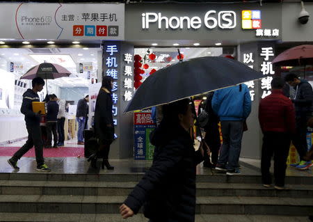 People walk past stores promoting the Apple iPhone 6S in the southern Chinese city of Shenzhen, January 26, 2016. REUTERS/Bobby Yip