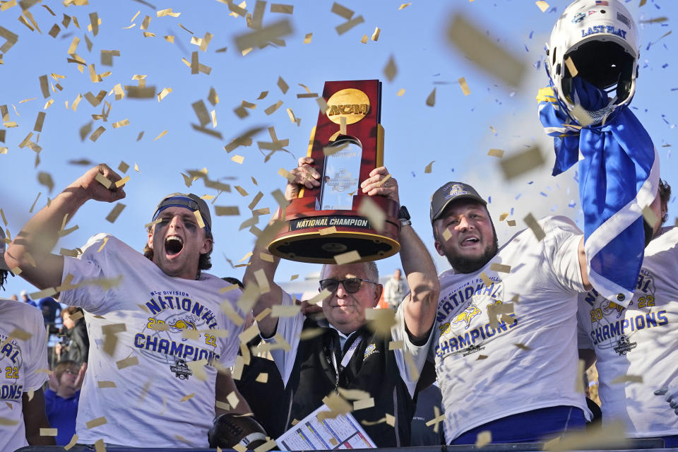 CORRECTS TO NORTH DAKOTA STATE NOT NORTH DAKOTA - South Dakota State head coach John Stiegelmeier, center, celebrates with quarterback Mark Gronowski, left, and offensive lineman Mason McCormick with the trophy after their team defeated North Dakota State to win the FCS Championship NCAA college football game, Sunday, Jan. 8, 2023, in Frisco, Texas. (AP Photo/LM Otero)