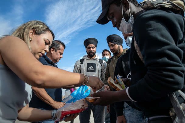 PHOTO: In this Dec. 9, 2021, file photo, immigrants from India and Haiti receive food from good Samaritans as they wait to be transported to a U.S. Border Patrol processing center in Yuma, Ariz. (John Moore/Getty Images, FILE)