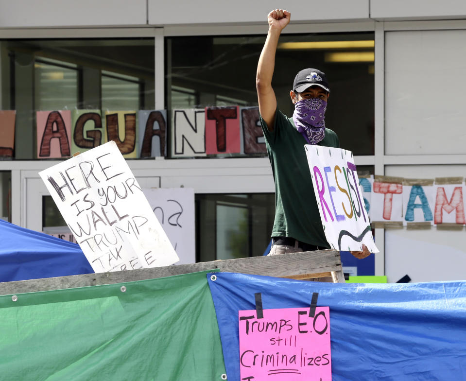 <p>An unidentified man holds a sign behind a makeshift wall at a protest camp on property outside the U.S. Immigration and Customs Enforcement office in Portland, Ore., Monday, June 25, 2018. (Photo: Don Ryan/AP) </p>