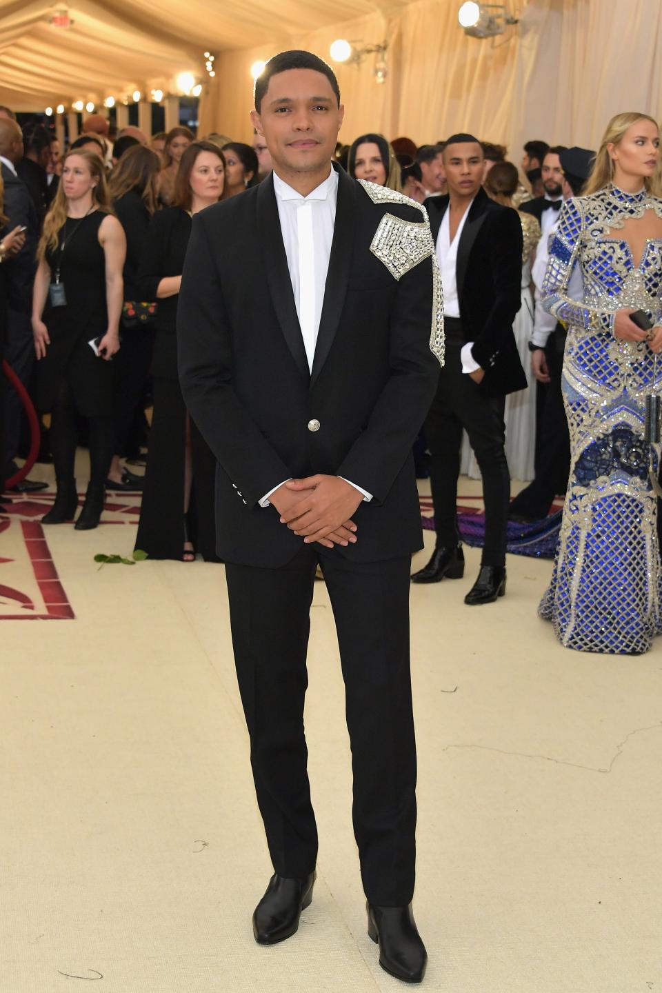 trevor noah wears a suit with a large, sparkling cross on its shoulder at the Met Gala 2018.