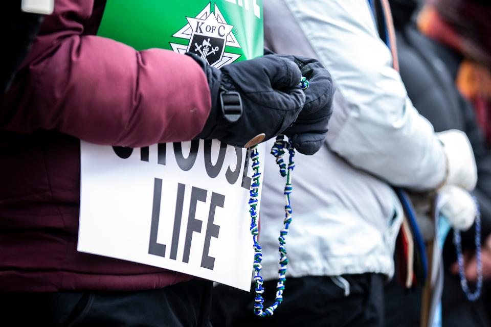 An anti-abortion activist prays while holding a rosary during a March for Life rally, Saturday, Jan. 21, 2023, in Iowa City, Iowa.