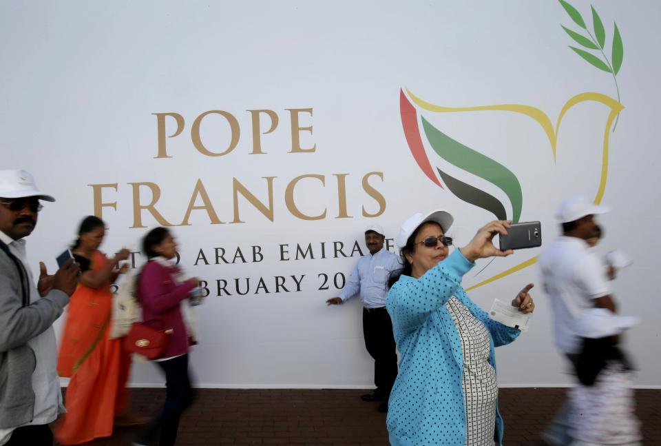 FILE- In this Tuesday, Feb. 5, 2019 file photo, worshippers take selfie in front of a sign on the Pope Francis Mass at the Zayed Sports City in Abu Dhabi, United Arab Emirates. The United Arab Emirates has been embarking on a yearlong, nationwide project to promote and brand state efforts under theme of "tolerance", but as 2019 inevitably comes to an end, a leading Emirati diplomat said Wednesday there's still much more work to be done. (AP Photo/Kamran Jebreili, File)