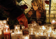 A woman adjusts a flower in front of candles and pictures displayed in tribute to singer Jenni Rivera at the Plaza Mexico shopping center in Lynwood, Calif., early Monday, Dec. 10, 2012. Authorities have not confirmed her death, but Rivera’s relatives in the U.S. say they have few doubts that she was on the Learjet 25 that disintegrated on impact Sunday in rugged territory in Nuevo Leon state in northern Mexico. (AP Photo/Patrick T. Fallon)