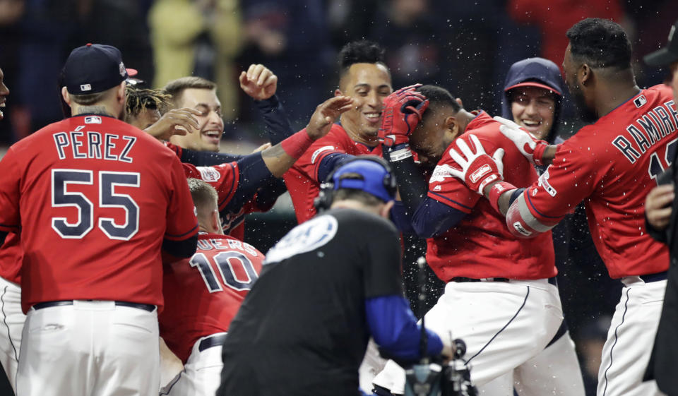 Cleveland Indians' Carlos Santana is mobbed by teammates after hitting a solo home run off Toronto Blue Jays relief pitcher Joe Biagini during the ninth inning of a baseball game Friday, April 5, 2019, in Cleveland. The Indians won 3-2. (AP Photo/Tony Dejak)