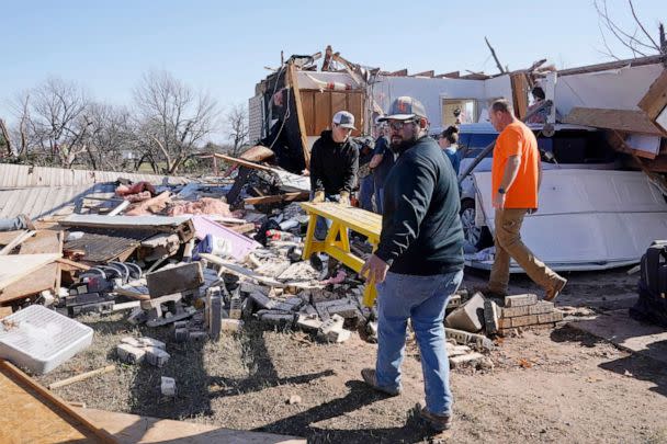 PHOTO: Adam Lee, left, and Jr. Ibarra, right, carry a table from a friend's home after it was destroyed by a tornado, Dec. 13, 2022, in Wayne, Okla. (Sue Ogrocki/AP)