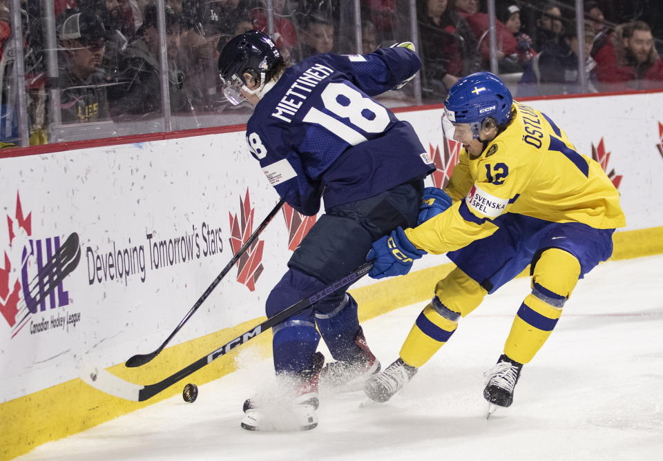 Finland's Vemer Miettinen and Sweden's Noah Ostlund fight for a loose puck during the third period of a quarterfinal hockey match at the world junior championship in Moncton, New Brunswick, Monday, Jan. 2, 2023. (Ron Ward/The Canadian Press via AP)
