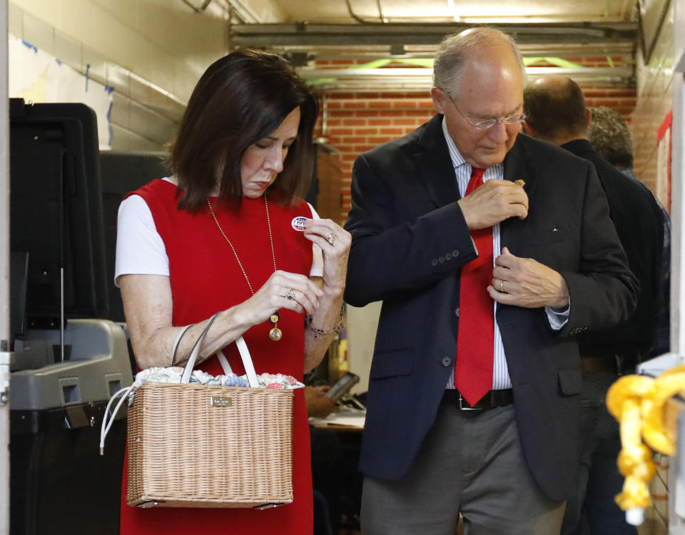 Former Mississippi Supreme Court Chief Justice Bill Waller Jr., a candidate for the GOP nomination for governor, right, and his wife Charlotte Waller, put their "I voted" stickers on their clothes as they exit their north Jackson, Miss., precinct, Tuesday, Aug. 27, 2019. Waller faces Lt. Governor Tate Reeves in the runoff for the GOP nomination for governor. (AP Photo/Rogelio V. Solis)