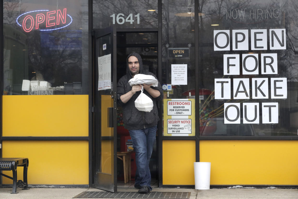 A man picks up takeout food in a restaurant in Rolling Meadows, Ill., Friday, March 27, 2020. Some restaurants are offering takeout and delivery service during the coronavirus pandemic. (AP Photo/Nam Y. Huh)