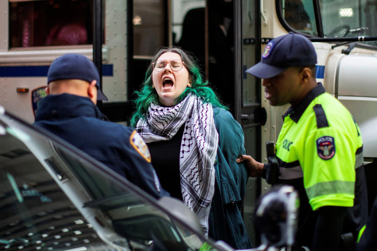 Two police officers detain a protester outside Rockefeller Center. 