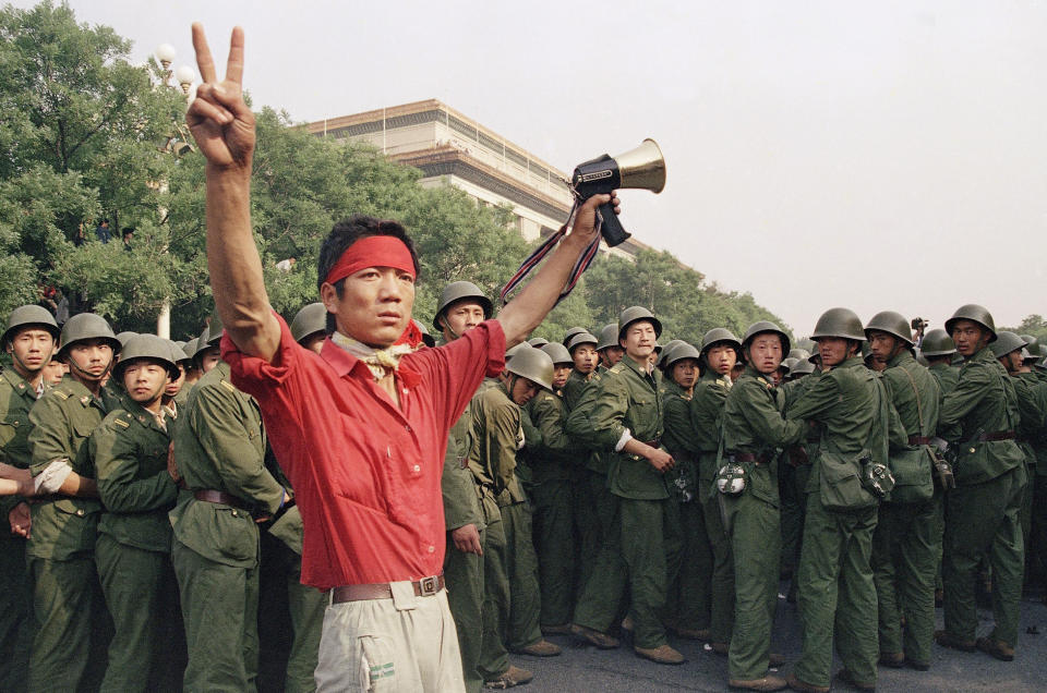 FILE - In this Saturday, June 3, 1989 file photo, a student pro-democracy protester flashes victory signs to the crowd as People's Liberation Army troops withdraw on the west side of the Great Hall of the People near Tiananmen Square in Beijing. Over seven weeks in 1989, the student-led pro-democracy protests centered on Beijing’s Tiananmen Square became China’s greatest political upheaval since the end of the decade-long Cultural Revolution more than a decade earlier.(AP Photo/Mark Avery, File)