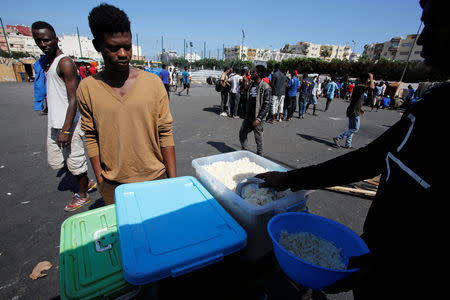 A man distributes food to African migrants at a makeshift home on the outskirts of Casablanca, Morocco September 5, 2018. REUTERS/Youssef Boudlal