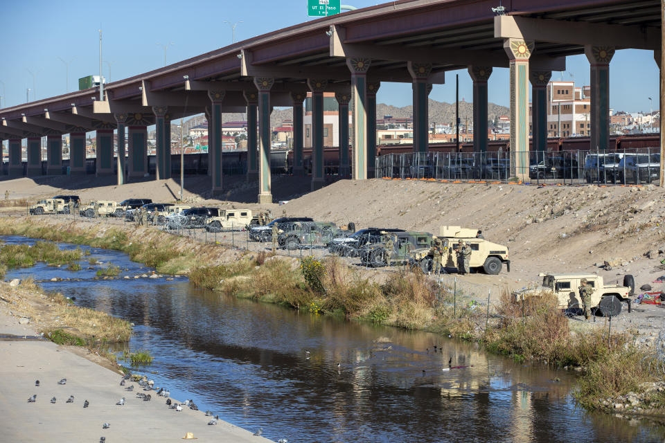 Texas National Guards line up their armored vehicles in the northern bank of the Rio Grande to prevent migrants from approaching the border fence in their attempt to enter into El Paso, Texas from Ciudad Juarez, Mexico, Wednesday, Dec. 21, 2022. (AP Photo/Andres Leighton)