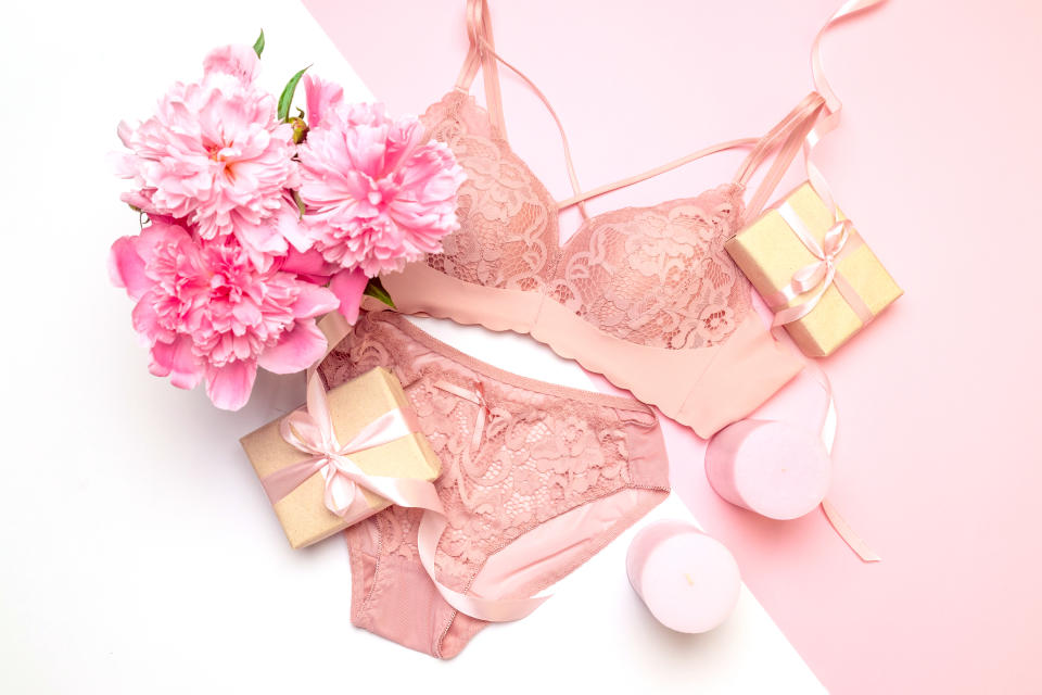 Female elegant pink lace bra and panties, flowers pink candles, a bouquet of beautiful peonies, gifts with pink ribbons, top view