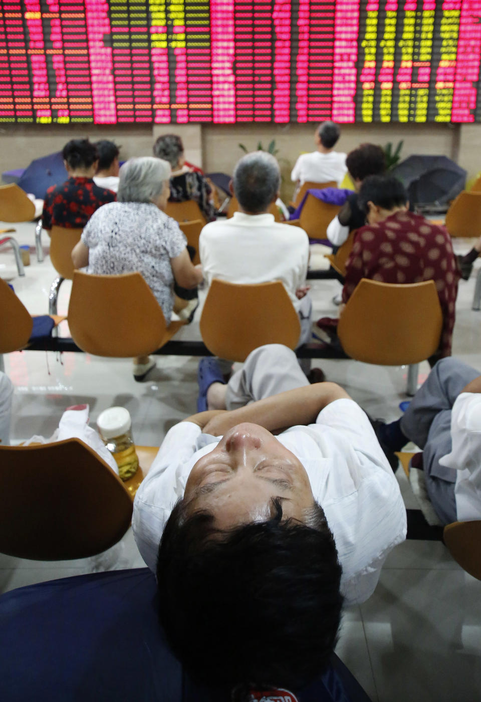 An investor takes a nap at a private securities company Tuesday, Sept. 4, 2012, in Shanghai, China. Asian stock markets fell Tuesday as uncertainty persisted about what authorities in the U.S., China and Europe might do to deal with a souring global economy. (AP Photo)